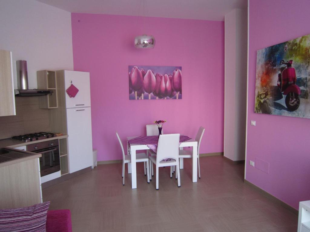 uma cozinha com uma mesa e cadeiras e uma parede roxa em Basculla Apartments em Gagliano del Capo