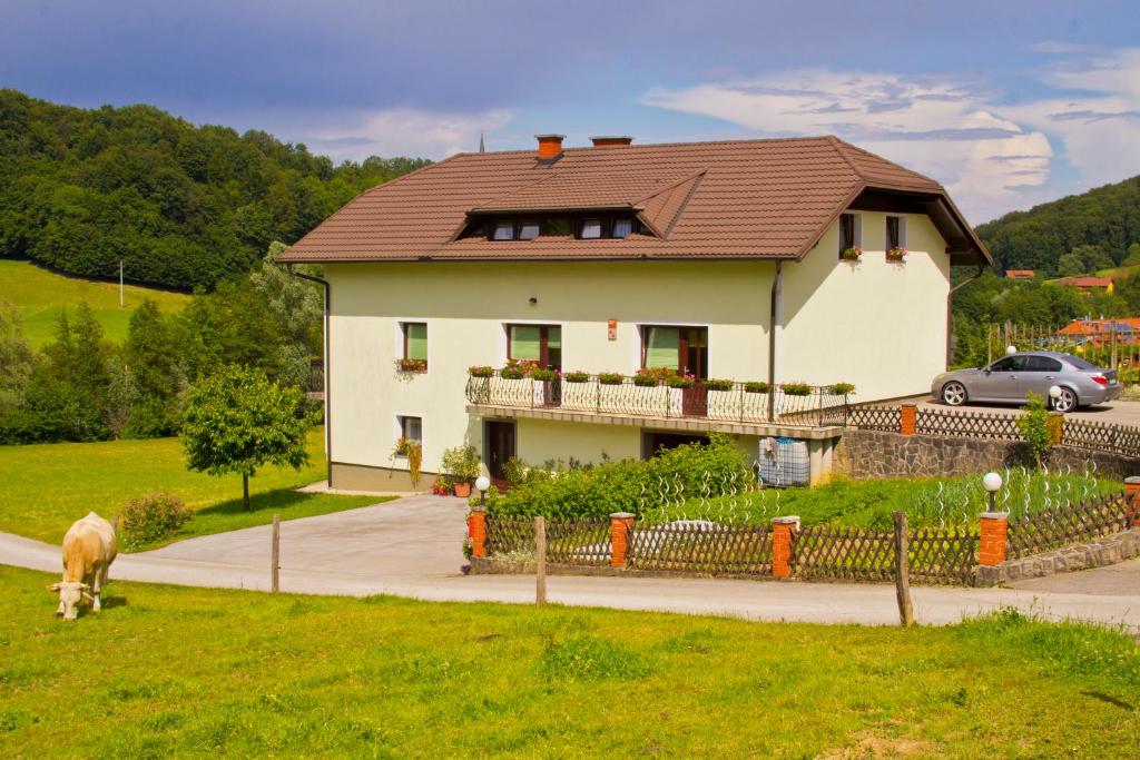 a house with a dog grazing in the grass at Tourist farm Mraz in Podčetrtek