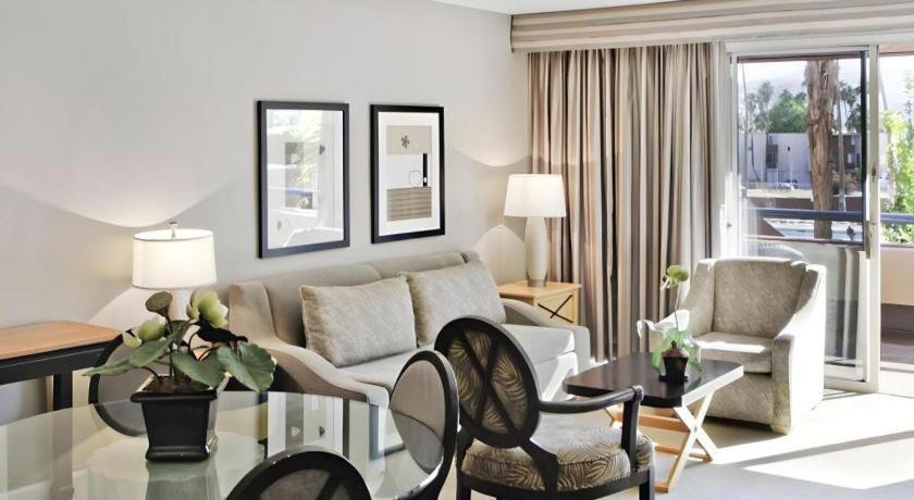 Marquis Villas Resort في بالم سبرينغز: غرفة معيشة مع أريكة وطاولة وكراسي