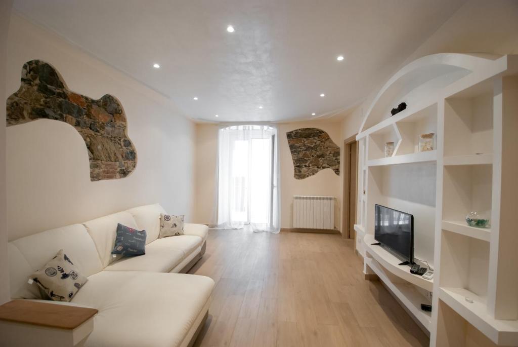 a living room with a white couch and a television at Arba Spaa Apartments in La Spezia