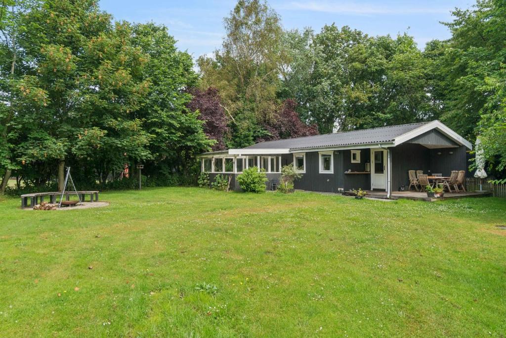 une petite maison dans une cour avec un champ d'herbe dans l'établissement Lovely Cottage Close To Beach And Nature, à Yderby