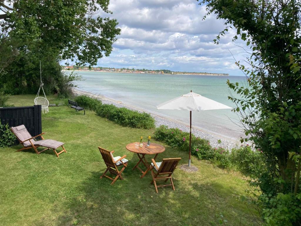 a table with chairs and an umbrella next to the beach at Holiday Home By The Water In Rødvig, Stevns in Rødvig