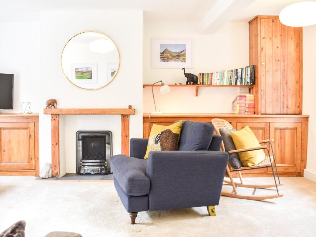 a living room with a blue chair and a fireplace at Riverside Cottage in Keswick