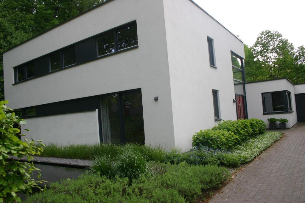 a white house with black windows and a brick driveway at Avellano in Helmond