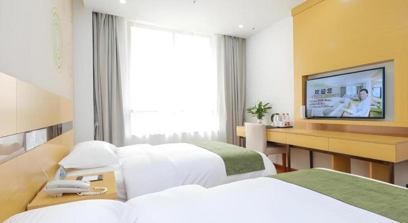 ein Hotelzimmer mit zwei Betten und einem Flachbildfernseher in der Unterkunft GreenTree Inn Jiaxin Puyuan Kaixuan Road in Puyuan