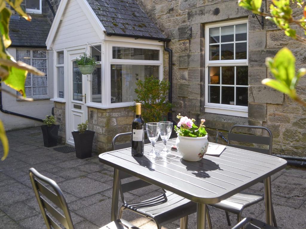 a table with a bottle of wine and glasses on a patio at Conway - Cottage in Rothbury