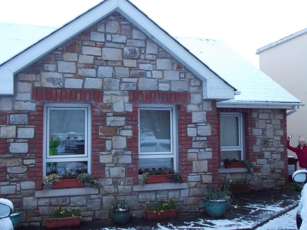 uma casa de pedra com neve no telhado em Reads Park Self - Catering Accommodation em Galbally