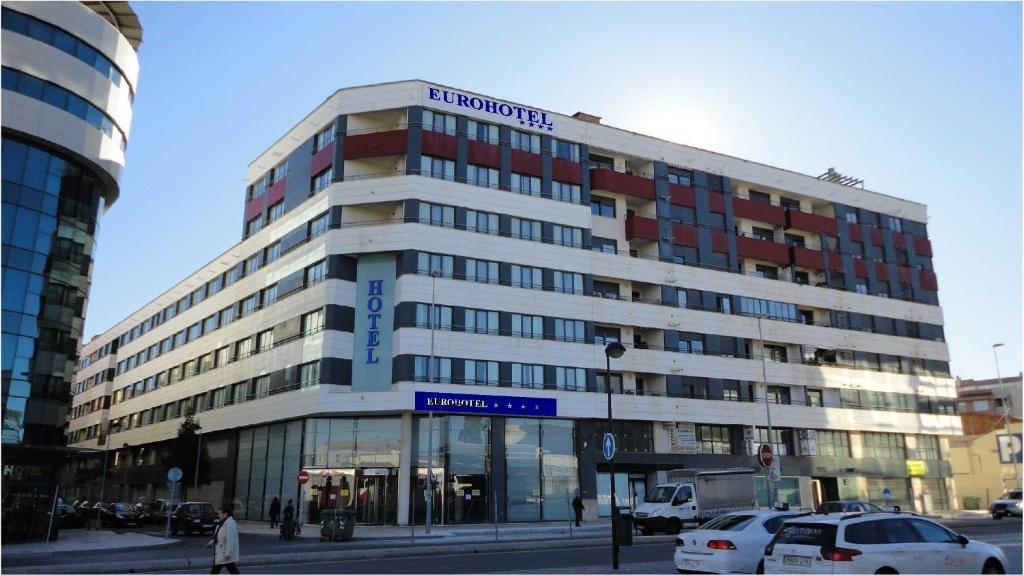 un gran edificio con coches estacionados frente a él en Eurohotel Castellón en Castellón de la Plana