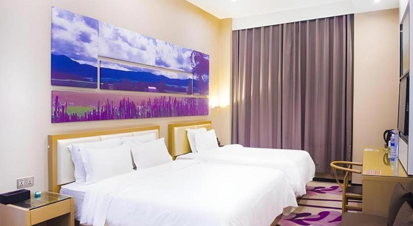 a hotel room with two beds and a painting on the wall at LAVANDE Hotel Dalian Huanan Square North Railway Station in Dalian