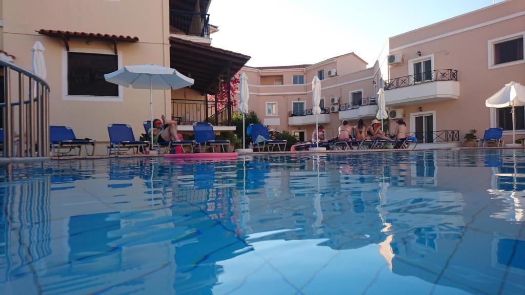 a swimming pool in a resort with people sitting on chairs at Doras Zante Studios & Apartments in Argassi