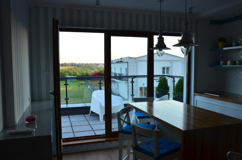 a kitchen with a table and chairs and a balcony at Błękitna Laguna in Puck