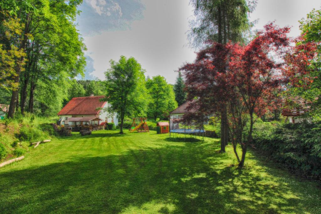 einen grünen Hof mit einem Haus und Bäumen in der Unterkunft Orange House in Kladenské Rovné