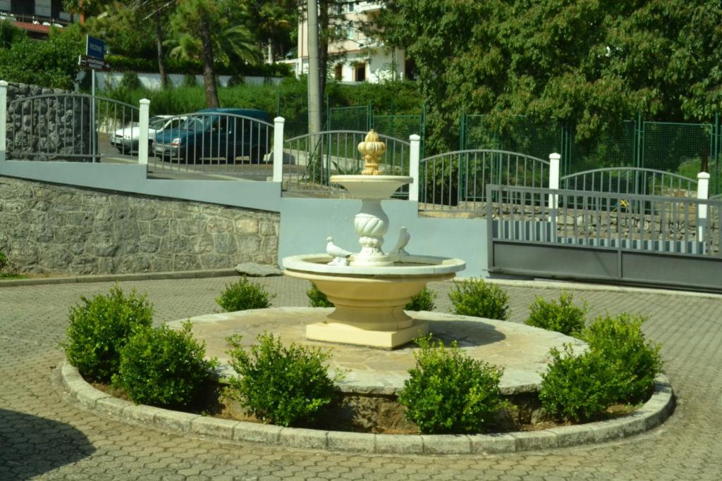 a fountain in the middle of a courtyard with bushes at Apartments Mirna with parking in Lovran
