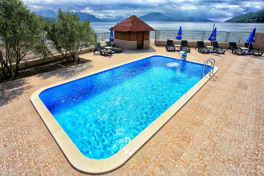 uma grande piscina azul com um gazebo em Apartments Maxi Katić em Herceg Novi