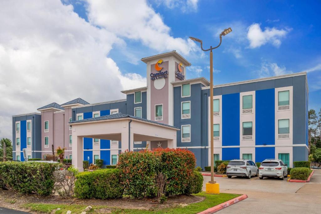 a blue and white building with cars parked in a parking lot at Comfort Inn & Suites Houston FM1960 - Champions in Houston