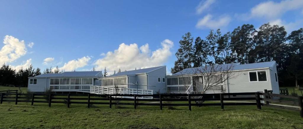 ein Mobilheim auf einem Feld neben einem Zaun in der Unterkunft Te Tihi Noho Shared Accommodation 