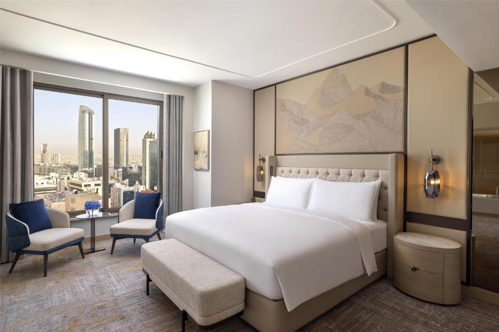 a bedroom with a large white bed and a large window at Signia by Hilton in Amman