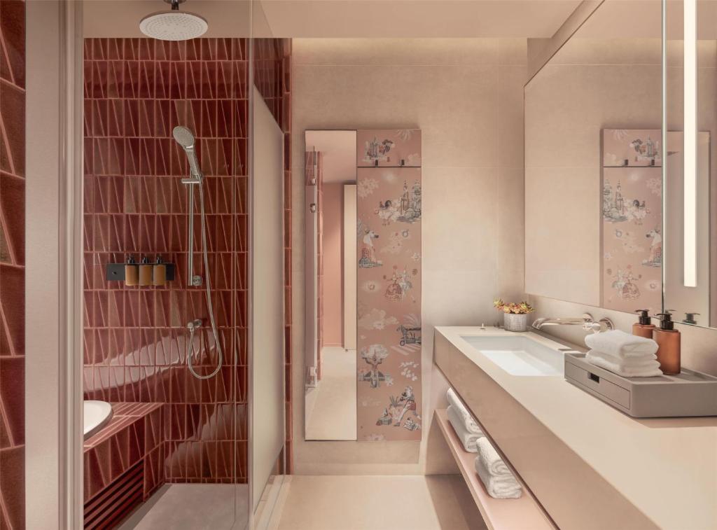 A warm-toned bathroom with a walk-in rain shower, long vanity, and generous mirror.