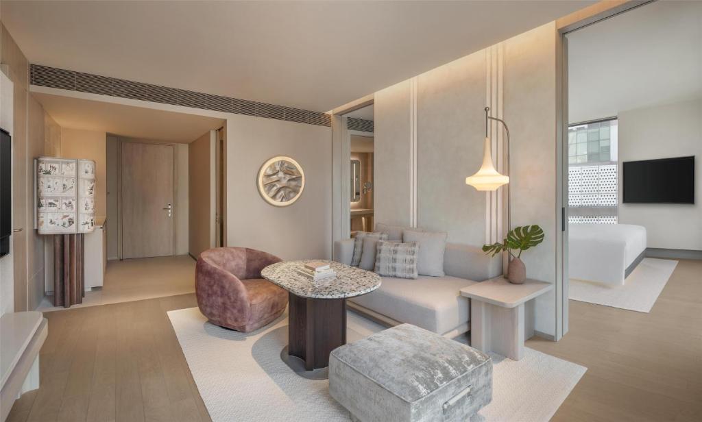 A lounge with a sofa, two occasional seats, and a view through to the bedroom.