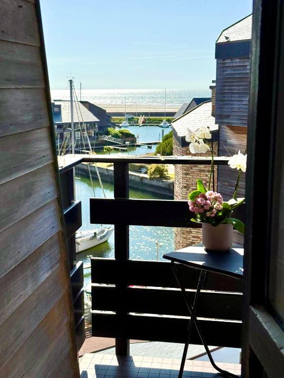 - un balcon avec une table et un vase de fleurs dans l'établissement Studio avec balcon vue mer, à Deauville