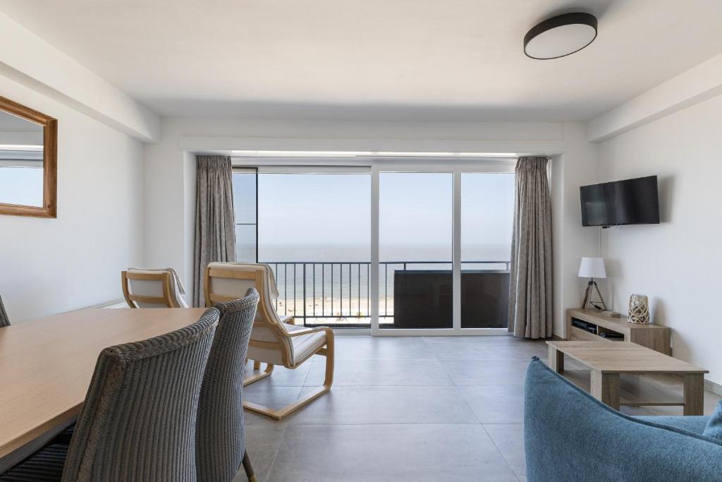 een woonkamer met een eettafel en uitzicht op de oceaan bij Santa Rosa in Blankenberge