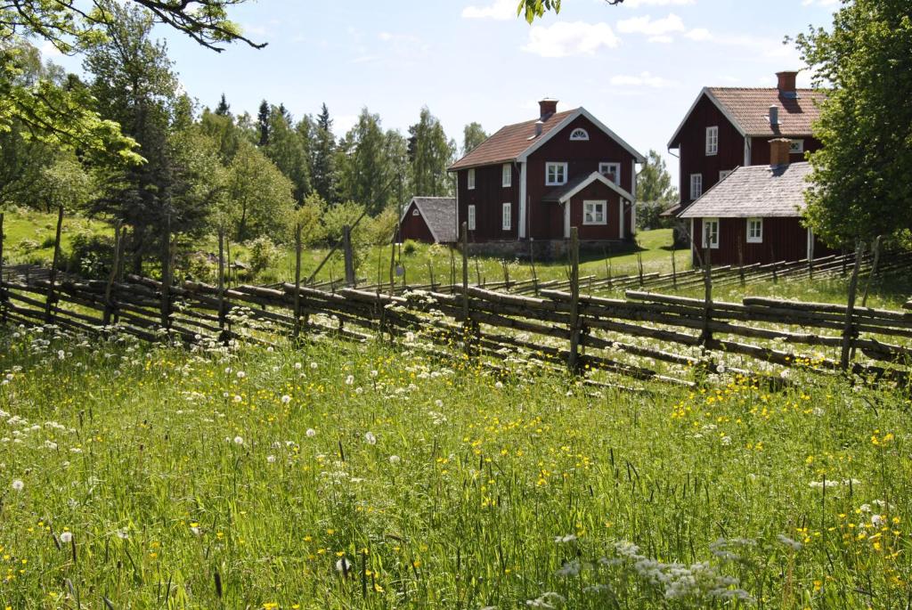 una granja con una valla y un campo de flores en Åsens By, en Haurida