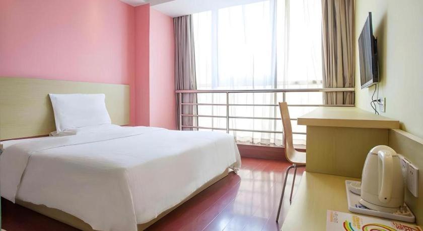 um quarto com uma cama branca e paredes cor-de-rosa em 7 Days Inn Chaozhou Chaofeng Road Bus Station em Chaozhou