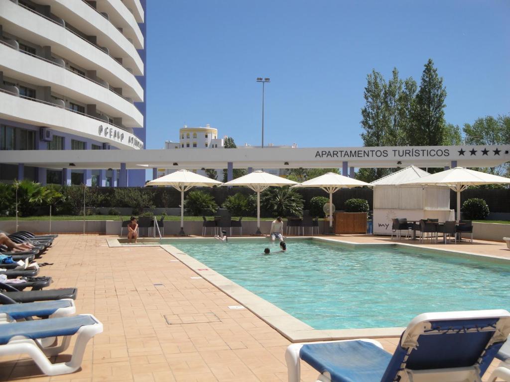 una piscina con sillas y sombrillas en un edificio en Deluxe Apart Ocean Beauty, en Portimão