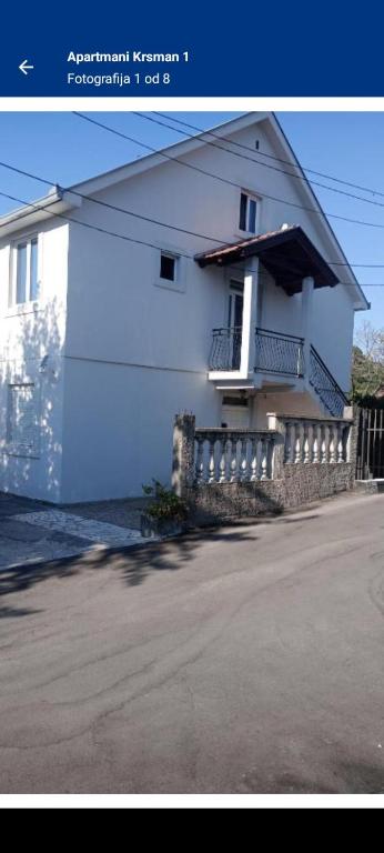 ein weißes Haus mit einem Balkon an der Seite in der Unterkunft Apartmani Krsman 2 in Herceg-Novi
