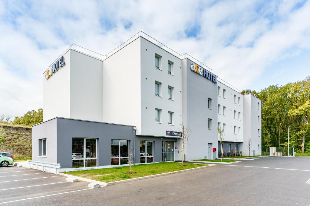 a large white building with a parking lot at ACE Hôtel Metz in Metz