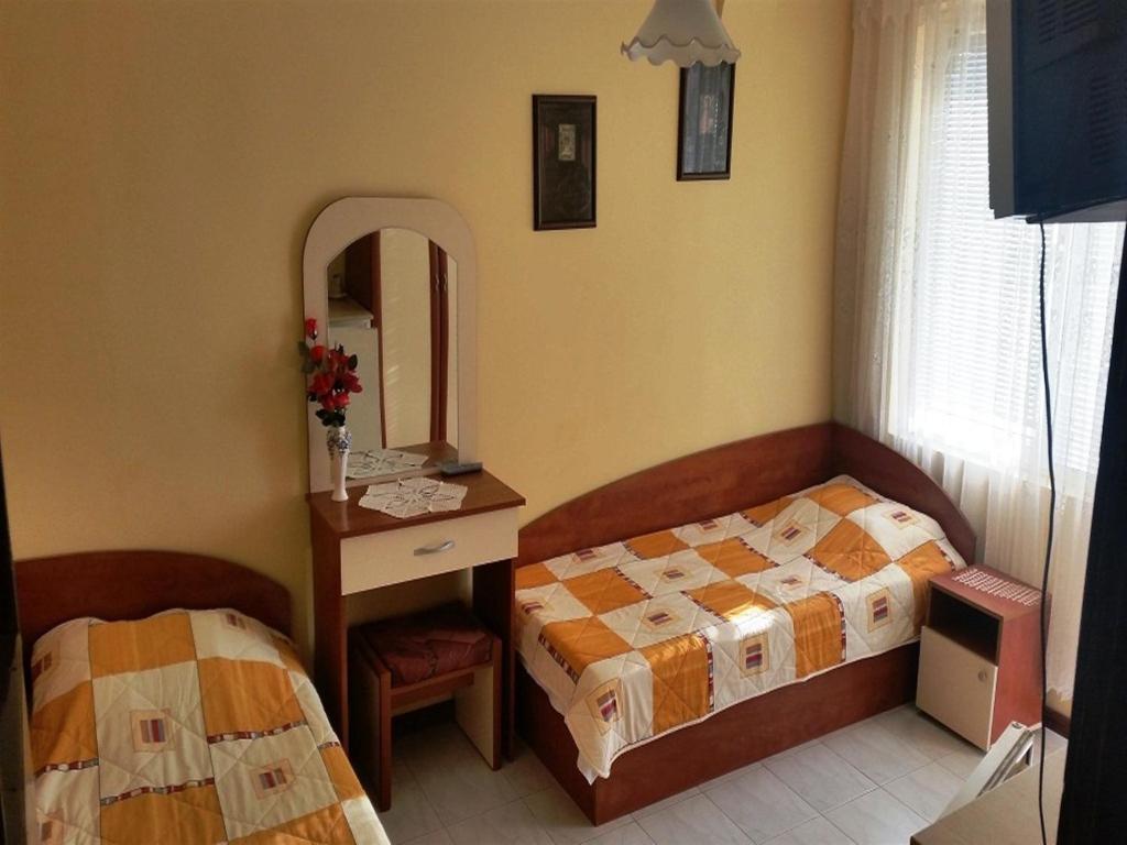 a bedroom with two beds and a mirror at Guest House Konomaevi in Sozopol