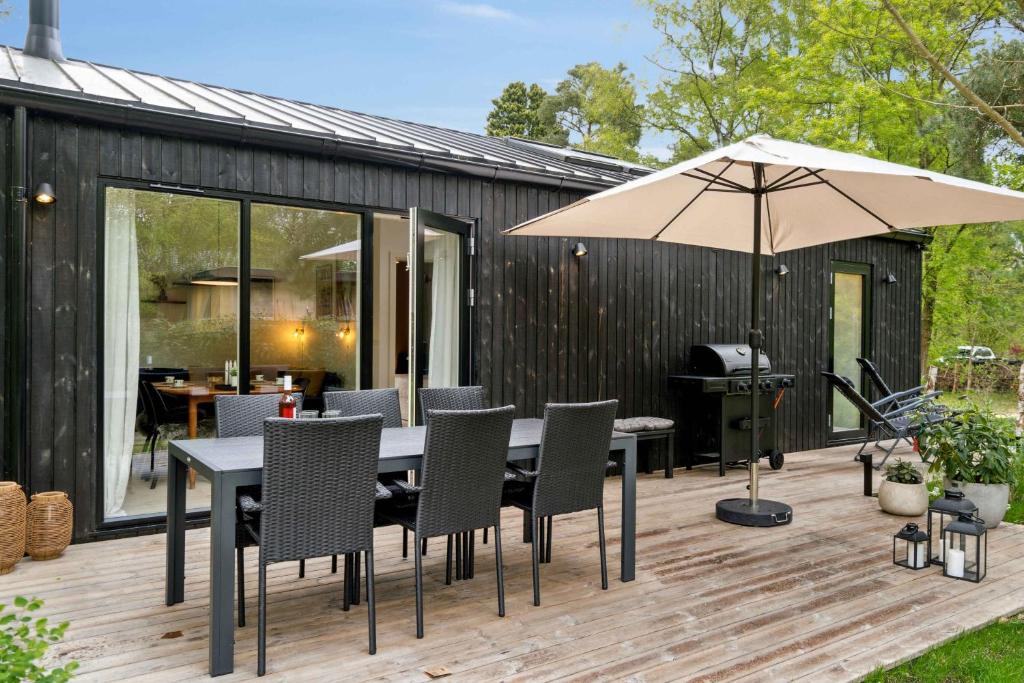 a deck with a table and chairs and an umbrella at New House Near Asserbo Plantation And Arresø in Frederiksværk