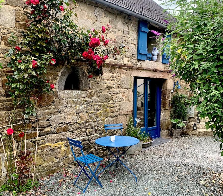 a table and two chairs in front of a stone building at La Grange avec Jacuzzi in Loguivy-Plougras