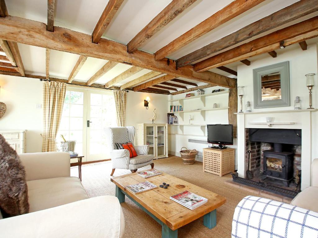 a living room with a fireplace and a table at Prospect Cottage in Wittersham
