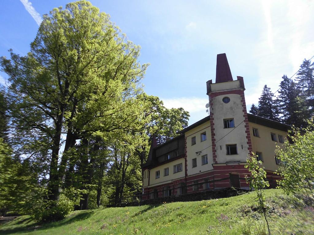 ein Gebäude auf einem Hügel mit einem Uhrturm darauf in der Unterkunft Turistická ubytovna Zámeček in Hojsova Stráž