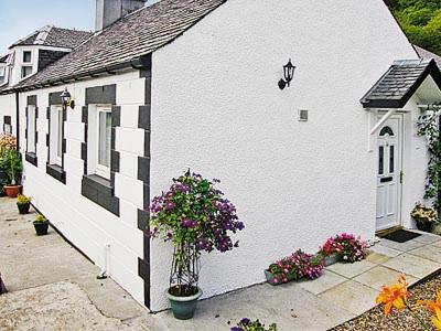 a white building with flowers on the side of it at The Old Store in Onich