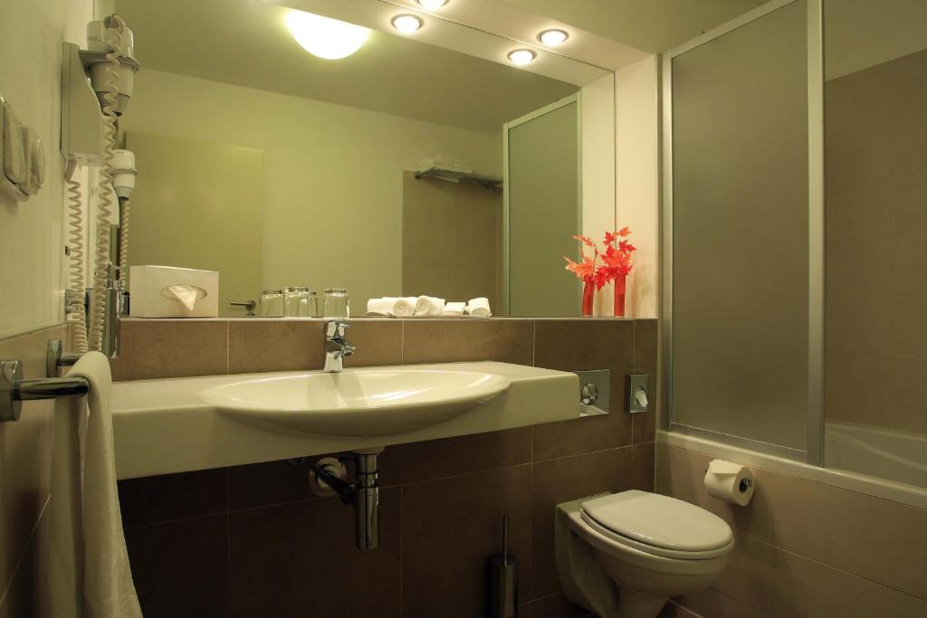 a bathroom with a sink and a toilet and a mirror at Hotel Páv in Prague