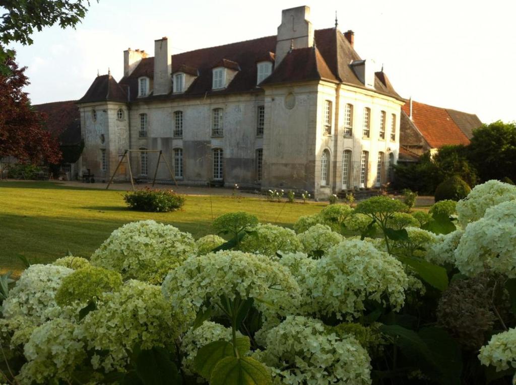 un viejo edificio con flores blancas delante de él en Ferme de la Vallière en Tancrou