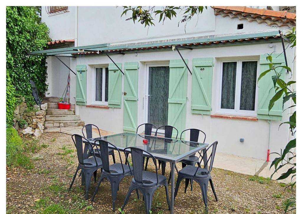 une table et des chaises en verre devant une maison dans l'établissement Bel appartement et son jardin, à Saint-Cézaire-sur-Siagne