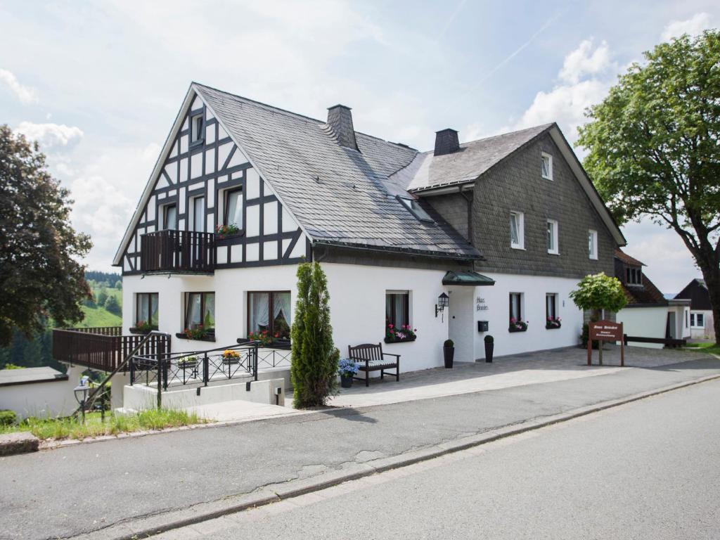 um edifício preto e branco com bancos em frente em Pension Haus Brieden em Winterberg