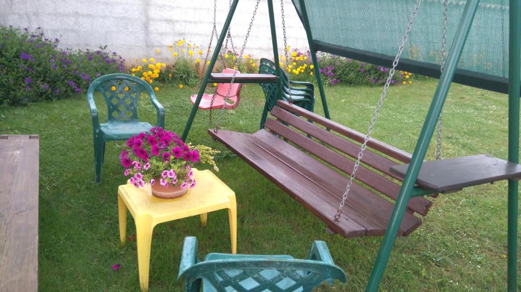 a swing and a table with a pot of flowers at Nella Apartments in Šišan