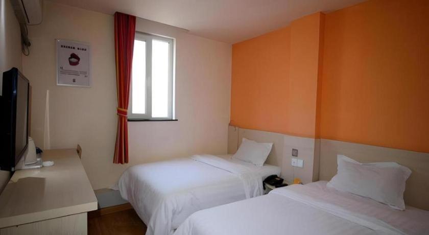a hotel room with two beds and a window at 7 Days Inn Yantai Dahaiyang Raod Railway Station in Yantai