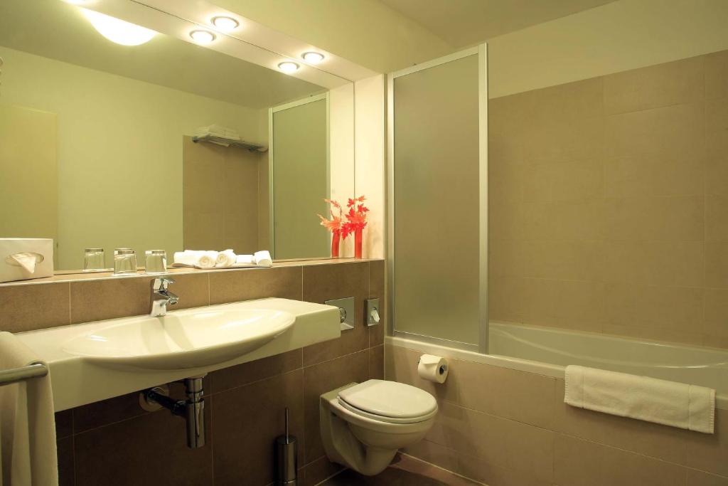 a bathroom with a sink and a toilet and a mirror at Hotel Páv in Prague