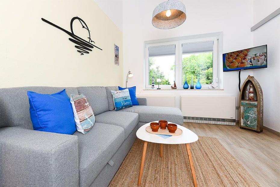 a living room with a gray couch and a table at Ferienwohnung Happynest in Bensersiel