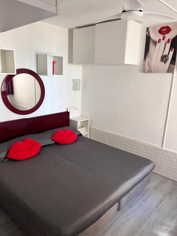 una camera da letto con un letto con cuscini rossi e uno specchio di Ocean view a Puerto Rico de Gran Canaria