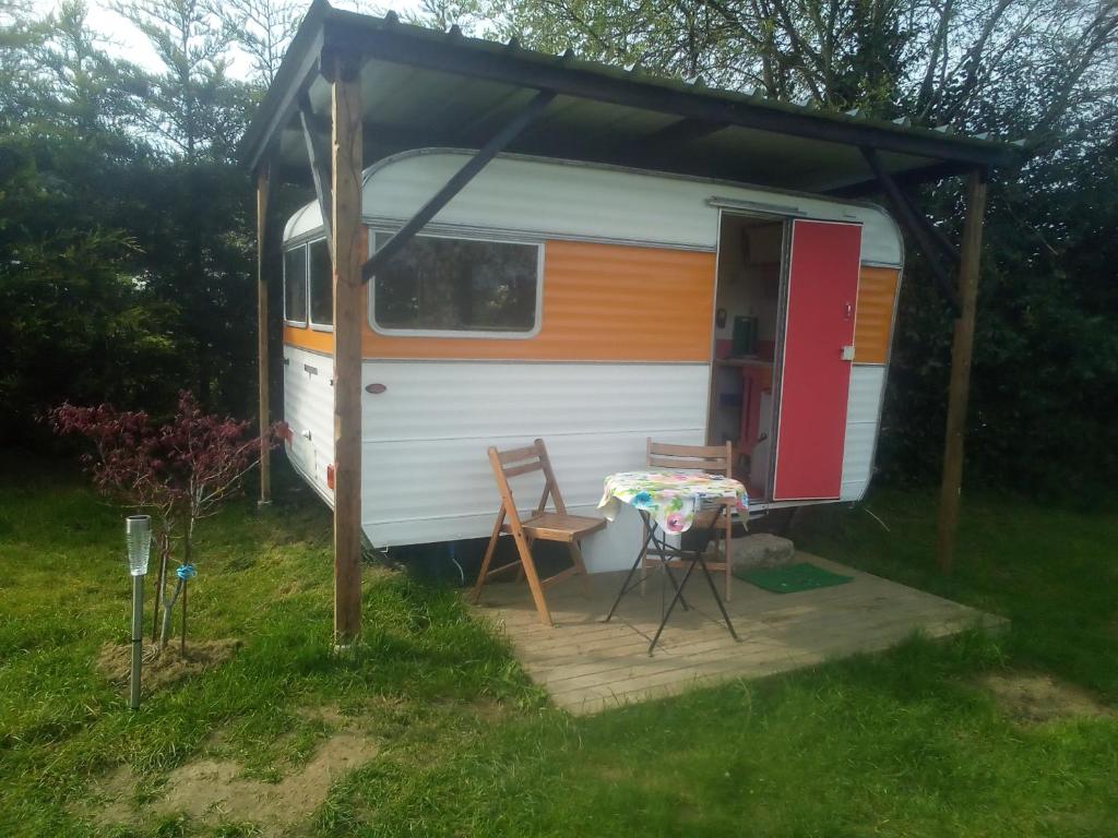 - un camping-car avec une table et des chaises devant dans l'établissement Unique 70s caravan, calm and relaxed, à Les Cresnays
