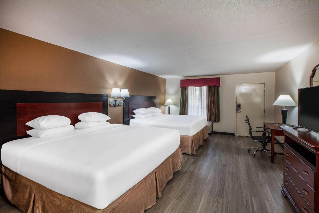 a hotel room with two beds and a television at Days Inn & Suites by Wyndham Tyler in Tyler