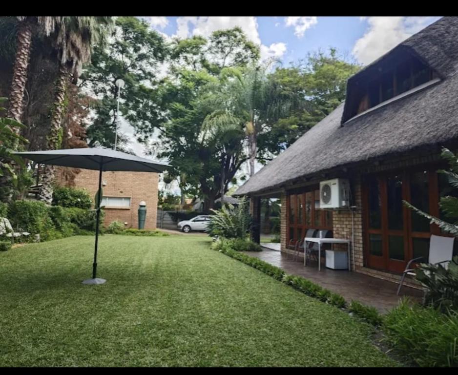 una casa con sombrilla junto a un patio en Wallace place guest house, en Polokwane