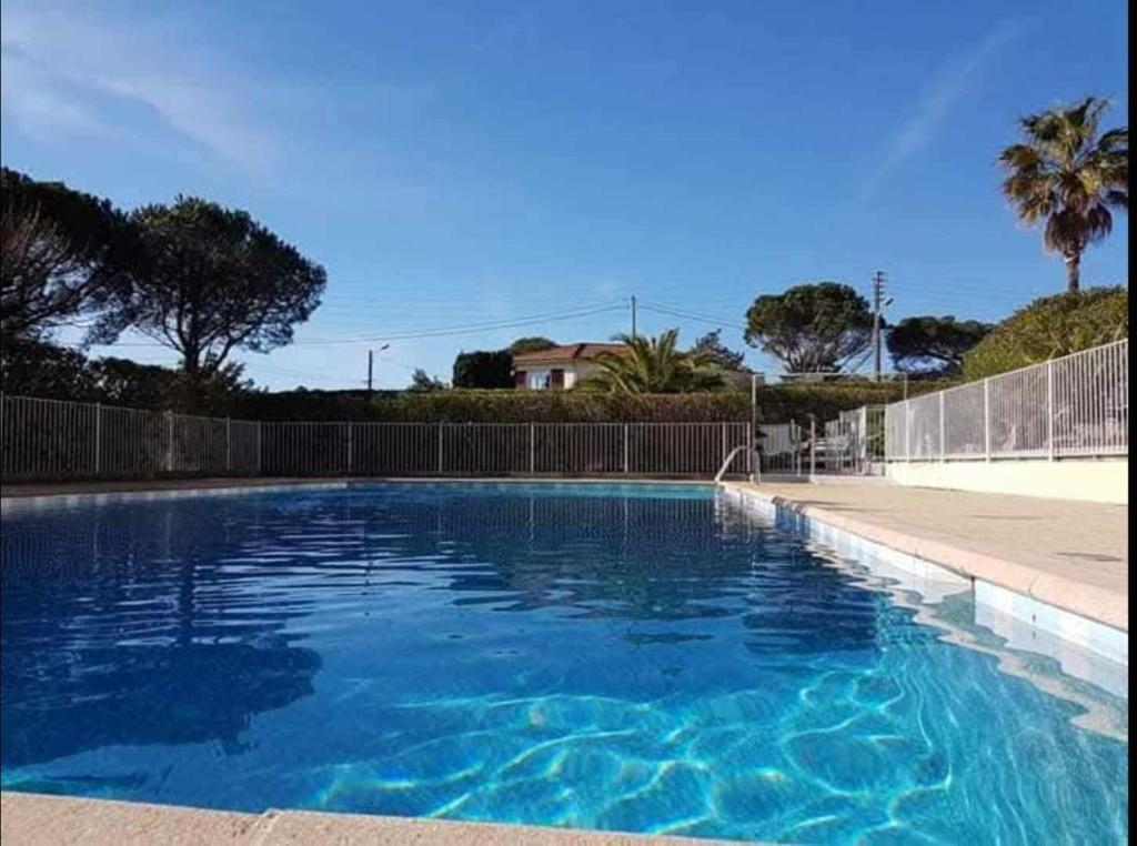 a large blue swimming pool in front of a fence at Soleil d'or à St Aygulf in Fréjus