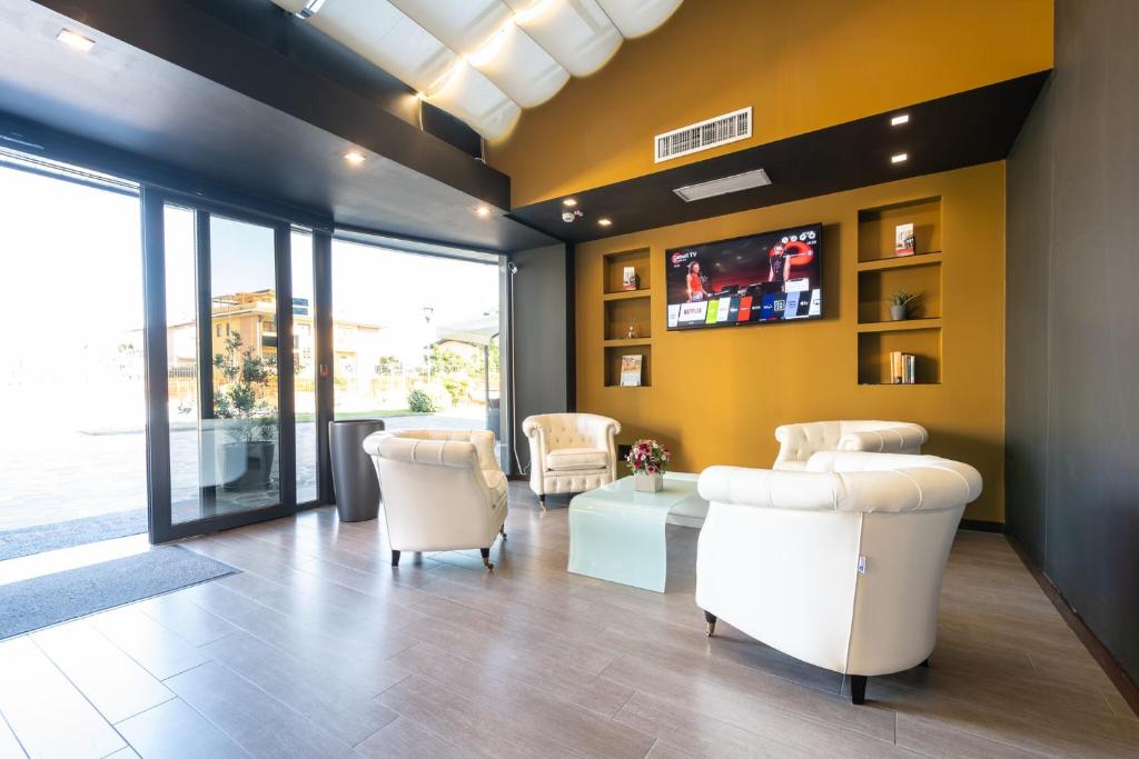 a living room with yellow walls and white chairs at Ferrari Hotel in Carugate